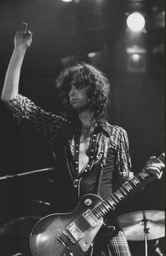 a man with long hair playing an electric guitar in front of microphones and lights