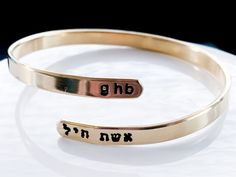 Celebrate your strength with this personalized wraparound bangle bracelet. Fashioned in brass, sterling silver, 14K gold filled, or 14K rose gold filled, this meaningful design showcases a trendy, sleek wraparound design. Complete this look with two names or phrases of your choice - each up to seven characters in length - inscribed in a tiny English and Hebrew font. FEATURES Adjustable - just slip on like a bangle bracelet and give a gentle squeeze 4.5-5mm wide Choose your wrist size and I will Personalized Spiritual Jewelry, Adjustable Engraved Bangle, Adjustable Spiritual Jewelry For Anniversary Gift, Adjustable Bangle Bracelets For Anniversary, Spiritual Bangle Bracelets For Anniversary, Customizable Adjustable Jewelry For Anniversary, Personalized Stackable Gold Jewelry, Adjustable Customizable Jewelry For Anniversary, Personalized Spiritual Bangle Bracelet