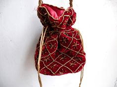 "Velvet evening purse with handwork of golden beads. Crossbody party bag with drawstring at the closure. It has an ethnic Indian touch in style and will go with western wears also like with dresses, jeans, etc. The bag is made up of velvet cloth in different color. It has a sling to hang it on the go. Can be used to gift some one or as fancy small sling bag in party or wedding. It can carry small things like mobile, wallet, etc. Dimension: maximum vertical length (of purse): 7\" vertical length Bohemian Beaded Potli Bag For Wedding, Traditional Evening Potli Bag With Latkans, Festival Beaded Potli Bag As A Gift, Beaded Shoulder Bag For Festivals Gift, Beaded Potli Bag For Festivals Gift, Beaded Potli Bag For Festivals And Gifts, Red Shoulder Bag For Festive Gift, Traditional Beaded Bag For Party, Festive Beaded Shoulder Bag As Gift