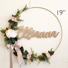 a wreath with flowers and the word aluna hanging from it's side in front of a white wall