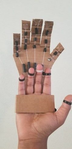 a person holding up several small pieces of paper with nails on them and black rings