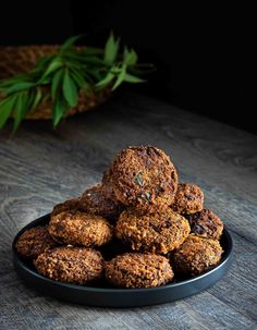 a black bowl filled with cookies on top of a wooden table next to a potted plant