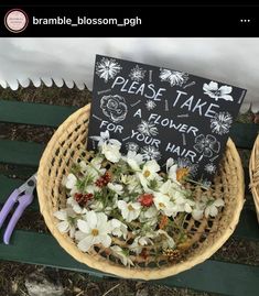 flowers in a basket with a sign that says please take a flower for your hair