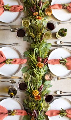 the table is set with white plates, silverware and orange napkins on it