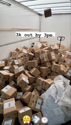 a pile of boxes sitting inside of a warehouse next to a white wall with the words 3k out by 9pm