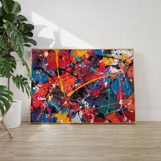 an abstract painting on the wall next to a potted plant