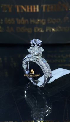 a diamond engagement ring sitting on top of a black table next to a card holder