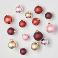 many different colored ornaments are arranged in a circle on a white surface, including one red and one gold ornament