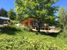 a couple of small cabins sitting on top of a lush green hillside next to trees