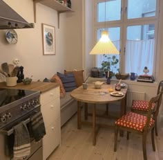 a small kitchen with a table, stove and chairs next to a window in the room