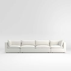 a white couch sitting on top of a white floor next to a wall with a light colored background