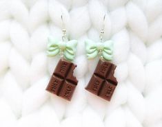 two pieces of chocolate with green bows on them are sitting on a white knitted surface