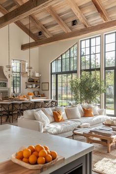 a living room filled with furniture next to a kitchen and dining room table in front of large windows