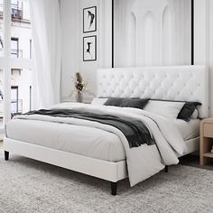 a white bed sitting in a bedroom on top of a carpeted floor next to a window