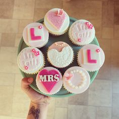 a person holding a plate with cupcakes decorated like hearts and the words i love you