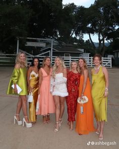 a group of women standing next to each other in front of a white fence and gate