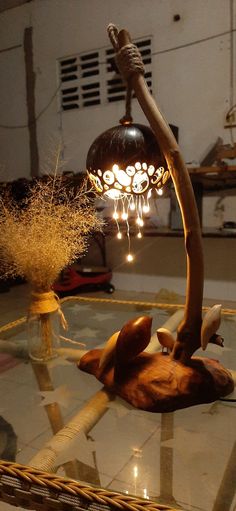 a lamp that is sitting on top of a table with flowers in the middle and lights hanging from it