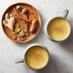 two mugs filled with different types of food on top of a white marble counter