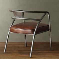 a brown leather chair sitting on top of a wooden floor next to a gray wall