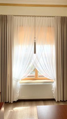 a window with sheer curtains and a radiator