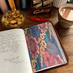 an open book sitting on top of a wooden table next to a bowl of cereal