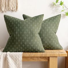 two green pillows sitting on top of a wooden bench