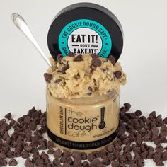 cookie dough in a jar with chocolate chips around it and a spoon on the side