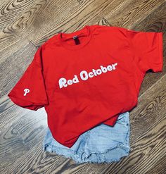 This is a unisex Phillies 'Red October' T shirt with small Phillies P on the sleeve. Only doing red shirts with white lettering at this time. F A B R I C 100% cotton S I Z I N G X Small, Small, Medium, Large and X Large are available.  C A R E * I N S T R U C T I O N Cold with like colors, turn inside out before washing and drying, tumble dry low, do not bleach, do not iron directly on the design, do not dry clean Red T-shirt With Funny Text For Summer, College T-shirt With Funny Text And Short Sleeves, Red Shirt With Text Print For Summer, Red Short Sleeve T-shirt With Letter Print, College Cotton T-shirt With Funny Text, Funny Text Cotton T-shirt For College, Red T-shirt For College Summer Events, Red T-shirt For College Summer, Red Slogan Crew Neck Shirt