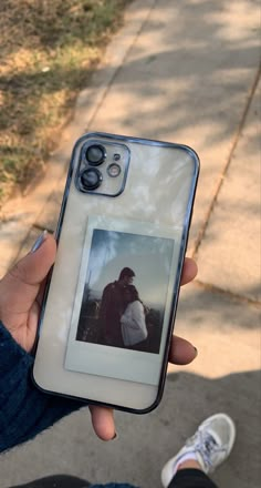 a person holding up a cell phone with an image on the back and side of it