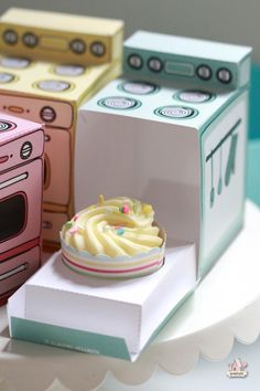 there are three boxes that have different types of cakes in them on the table, one is pink and one is green