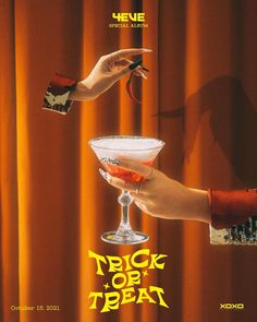 a hand holding a martini glass with the word trick o'treat on it and an orange curtain in the background