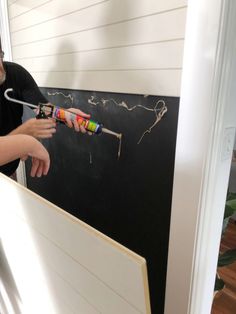 a man holding a paint roller near a blackboard