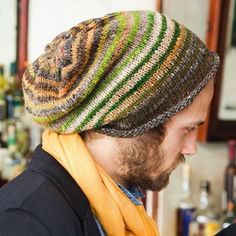 a man with a beard wearing a knitted hat and scarf in front of a bar