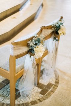 a wooden bench decorated with flowers and veils on it's seat cover for a wedding ceremony