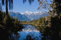 a lake surrounded by trees and mountains in the background