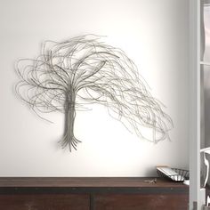 a metal sculpture on the wall above a dresser in a room with white walls and wooden furniture