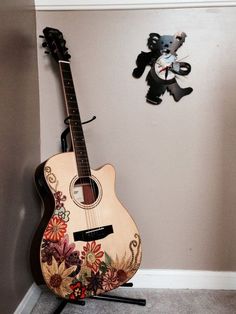 a wooden guitar sitting on top of a stand next to a teddy bear wall clock