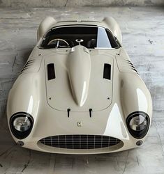 an old white sports car parked in a garage