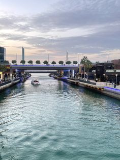 a waterway with boats in it and people walking on the side walk above water at dusk