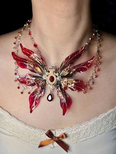 a woman wearing a necklace with red flowers on it