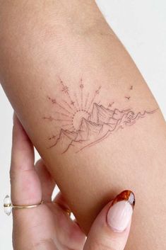 a woman's arm with a mountain tattoo on it