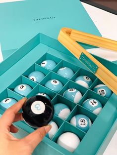 a person is holding a pool ball in a blue box with numbers on the inside