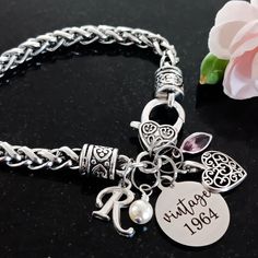 a close up of a bracelet on a table with a flower and a rose in the background