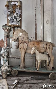 an old fashioned wooden horse and lamb on a cart in front of a white painted wall