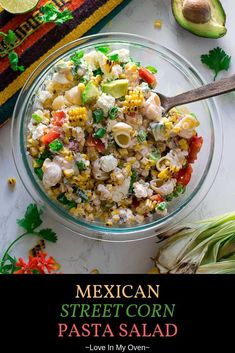 mexican street corn pasta in a glass bowl next to an avocado and cilantro