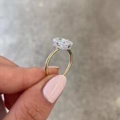 a woman's hand holding an engagement ring with a diamond on the top and side