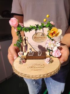 a person holding a piece of art made out of wood with flowers and leaves on it