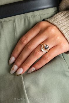 a woman's hand wearing a gold ring and green pants, with her left hand on the lap