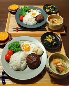 two plates with food on them sitting on a table next to bowls and utensils