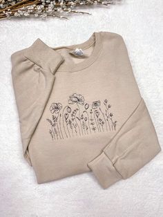 "Embroidered Wildflower Crewneck Sweatshirt, Cute Flower Hoodie. The sweatshirt is a soft spun crewneck and is very soft cotton poly blend, which is so comfy. Embroidered design will be as shown as in the picture. Personalization section: You will need to choose your thread color in this section. Item Description: Unisex Men Sizing Cotton and Polyester Pull On Long Sleeve Crewneck It takes 1-2 weeks to make and process orders for shipping. If you require it sooner, you will need to purchase the Cute Crew Neck Designs, Embroidery Design Sweatshirt, Crew Neck Design Ideas, Emboridary Designs Sweatshirt, Fall Floral Embroidered Crew Neck Sweater, Spring Crew Top With Embroidered Logo, Embroidered Cream Long Sleeve Sweatshirt, Casual Embroidered Cream Sweater, Simple Crewneck Design